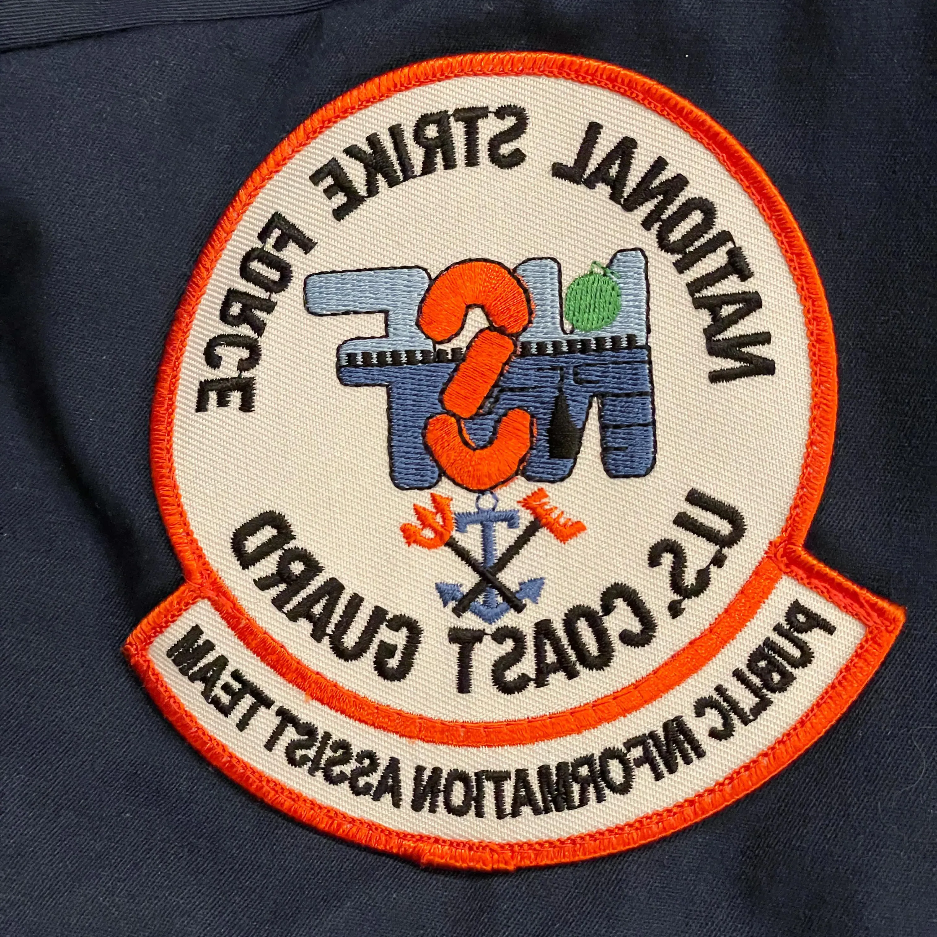制服上的徽章，上面写着“美国国家打击部队”.S. 海岸警卫队. 新闻协助小组”
